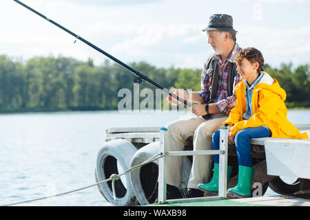 Reifer Mann angeln in der Nähe der Enkel sitzenden Bärtigen Stockfoto