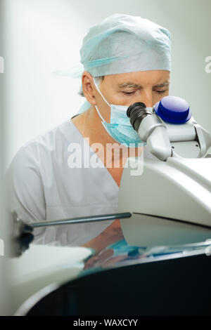 Ernsthafte hart arbeitende Arzt mit speziellen medizinischen Gerät Stockfoto