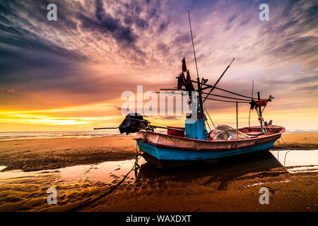 Schönen Sonnenaufgang über einem alten hölzernen Fischerboot auf einem Kiesstrand Stockfoto