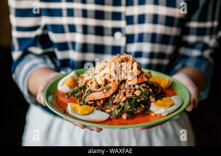 Thai home kochen Küche Seablite Seepweed Salat mit Garnelen und gekochtes Ei - Frau mit Schüssel Salat Seablite Stockfoto