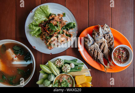 Nam Prik Pla, gebratener Fisch, würzige Fisch Salat, Tom Yum Suppe - Thai Street Food Lunch Set und frisches Gemüse, Kürbis, Gurken, Bohnen und Blumenkohl Stockfoto
