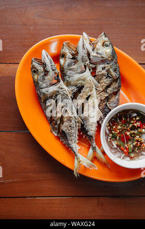 Thailändisches Essen am Tisch, Knusprig frittierte makerel Fisch auf bunte Platte auf Holz Tisch - Ansicht von oben geschossen Stockfoto