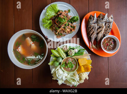 Nam Prik Pla, gebratener Fisch, würzige Fisch Salat, Tom Yum Suppe - Thai Street Food Lunch Set und frisches Gemüse, Kürbis, Gurken, Bohnen und Blumenkohl Stockfoto