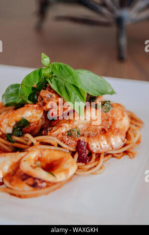 Würzige Italienisch Meeresfrüchte Spaghetti alle Sugo Arrabbiata mit frischem Basilikum auf die Oberseite in weiße Platte, Region Latium Nudelgerichte. Stockfoto