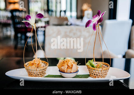 Thai verschiedene traditionelle knusprig gebratener Reis papier Snacks, Thung Tong, ei Snack und Krathong Tong auf weißer Keramik Platte auf Schwarzen Tisch Nahaufnahme Stockfoto