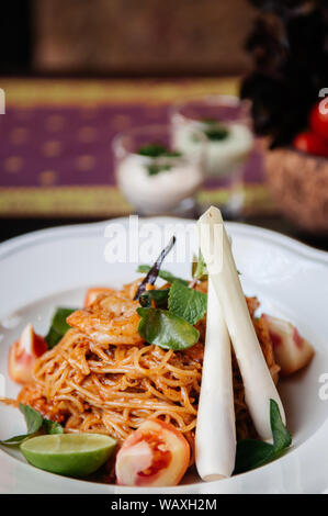 Nahaufnahme von Fusion spaghetti Garnelen Nudeln mit Thai Tom Yum Gung pikanter Sauce, kaffernlimette Blätter, Zitronengras und Tomaten/Paradeiser Stockfoto