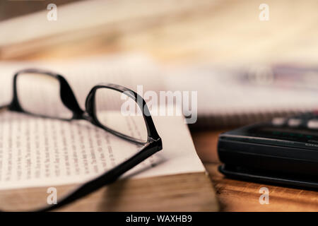 Bücher mit Brille auf einem hölzernen Tisch verstreut. Hintergrund Konzept für Prüfung studieren, arbeiten hart und Lehrer Tag mit Kopie für Text. Stockfoto