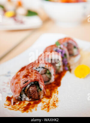 Frische schöne Stücke der japanischen Wagyu Beef Sushi maki Rollen und Soße auf Keramikplatte, schoß schließen Stockfoto