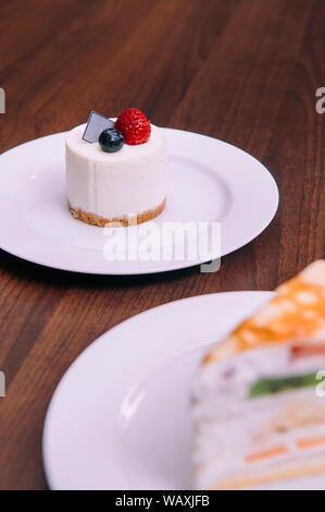 Cremige Käsekuchen mit Himbeeren und Blaubeeren auf weißem Teller in bekery Cafe. Nahaufnahme Nahrung Schuß Stockfoto