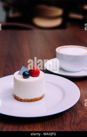 Cremige Käsekuchen mit Himbeeren und Blaubeeren auf weißem Teller in bekery Cafe. Nahaufnahme Nahrung Schuß Stockfoto