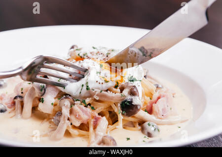 Essen Schuß von der italienischen Pasta Spaghetti mit cremigen Alfredo Sauce, Pilz und pochiertem Ei Stockfoto