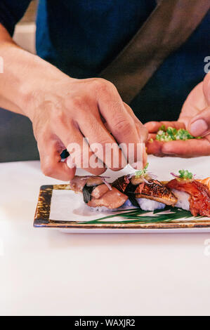 Asiatische legte Chef grüne Zwiebel auf viele Arten von japanischen Sushi auf Keramikplatte, Rindfleisch gehackt, Foie gras. Stockfoto