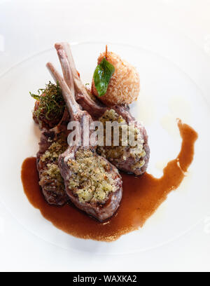 Kellner serviert gegrillte Lammkoteletts mit Kruste, Soße und frittierte Kartoffeln, aus nächster Nähe erschossen Stockfoto