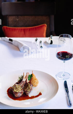 Kellner serviert gegrillte Lammkoteletts mit Kruste, Soße und frittierte Kartoffeln, aus nächster Nähe erschossen Stockfoto
