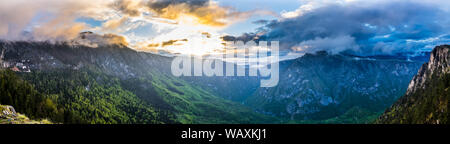 Montenegro, XXL Panorama von orange Sonnenuntergang Himmel und Wolken in Licht über Welt berühmten Fluss Tara Canyon Natur Landschaft vom Gipfel des Cu montieren Stockfoto