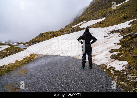 Montenegro, Frau, die auf dem geschlossenen Asphaltstraße von sedlo Pass Route blockiert durch Schnee in springtide im Monat Mai beim Versuch, durmitor Nat zu überqueren Stockfoto