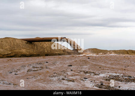 Rusty am Ufer, aus denen Abwasser fließt, schmutziger Sand Gülle Stockfoto