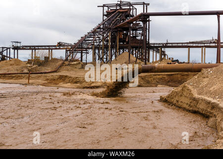 Rusty am Ufer, aus denen Abwasser fließt, schmutziger Sand Gülle, und stationären rusty Schwerkraft sand und kies Separator auf dem backgrou Stockfoto