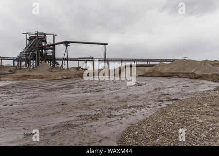 Rusty am Ufer, aus denen Abwasser fließt, schmutziger Sand Gülle, und stationären rusty Schwerkraft sand und kies Separator auf dem foregrou Stockfoto