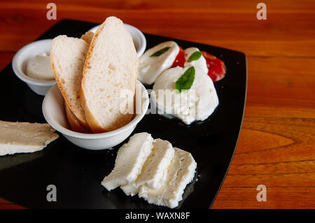 Baguette Scheiben Brot und frischen Mozzarella und verschiedene Käse aus Büffelmilch in schwarze Platte Stockfoto