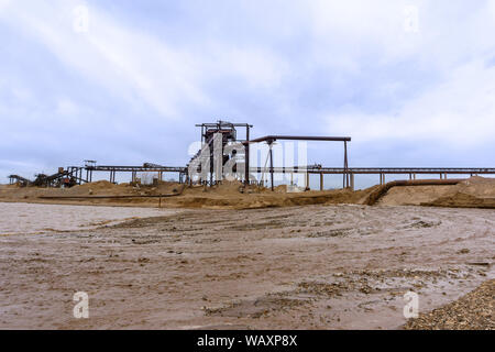 Rusty am Ufer, aus denen Abwasser fließt, schmutziger Sand Gülle, und stationären rusty Schwerkraft sand und kies Separator auf dem backgrou Stockfoto