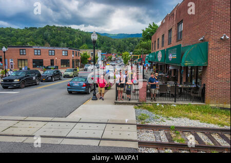 Bryson, North Carolina, USA - August 3, 2019: die Menschen Welle bei passenders auf einem Zug, vom Bürgersteig während Autos am Bahnübergang in der Stadt warten Stockfoto