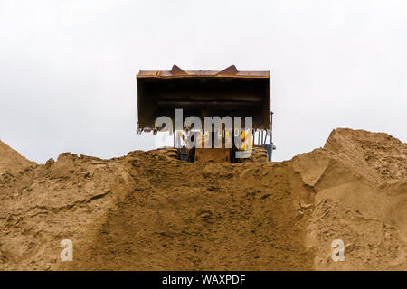 Ladeschaufel hat gerade Entladen der Sand auf sandigen Heap Stockfoto