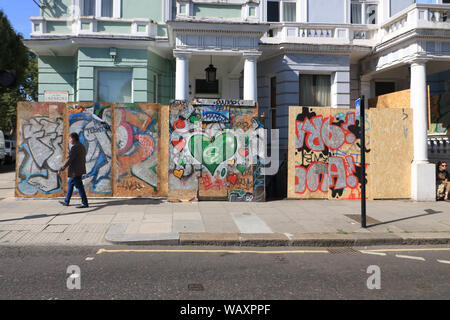 London, Großbritannien. 22 Aug, 2019. Ein Fußgänger geht Vergangenheit verbrettert Eigenschaften in Graffiti in Ladbroke Grove West London als Vorsorge gegen anti-soziales Verhalten während der größten Straßenfest der jährlichen Notting Hill Carnival Europas, feiert der karibischen Kultur mit Paraden. Credit: Amer Ghazzal/SOPA Images/ZUMA Draht/Alamy leben Nachrichten Stockfoto