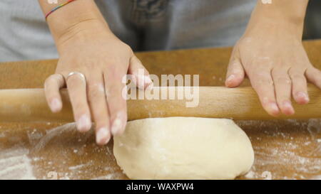 Die Frau oder der Mann auf dem Tisch rollen den Teig für Plätzchen, Pizza, Pasta aus Stockfoto