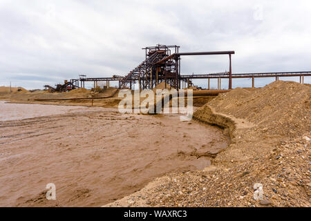 Rusty am Ufer, aus denen Abwasser fließt, schmutziger Sand Gülle, und stationären rusty Schwerkraft sand und kies Separator auf dem backgrou Stockfoto