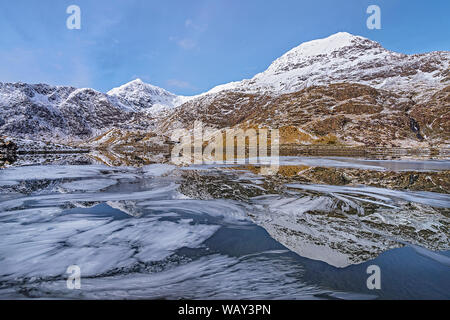 Krippe Goch Berge und den Mount Snowdon in Llyn Llydaw mit Eis auf der Wasseroberfläche Snowdonia National Park North Wales UK März 2018 wider Stockfoto