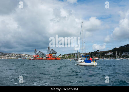 Kleines Boot die Übergabe eines Schwimmbaggers in Falmouth Harbour, Cornwall, England, Großbritannien Stockfoto