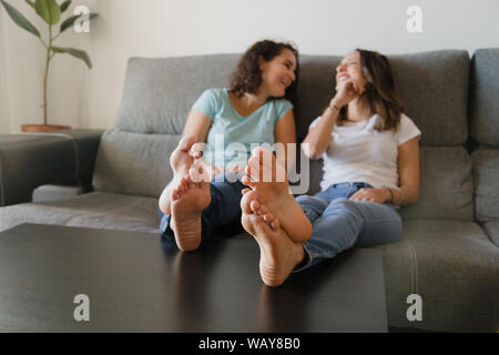 Mädchen in einer Couch mit Füßen in einer Tabelle lachen Stockfoto