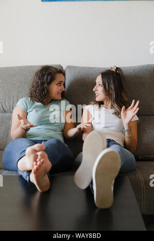 Mädchen in einer Couch mit Füßen in einer Tabelle sprechen Stockfoto