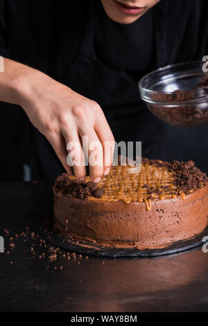 Männer Hände verzieren Kuchen mit Schokolade Stockfoto