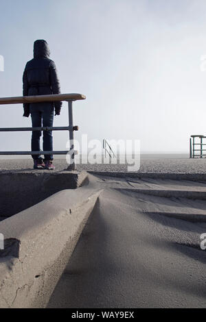 Ansicht der Rückseite mit Kapuze Person, die auf leeren Strand Stockfoto