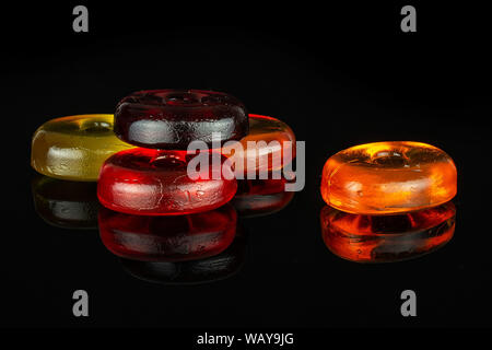 Gruppe von fünf ganze bunte Bonbons auf schwarzem Glas isoliert Stockfoto