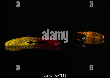 Gruppe von drei ganze Bunte Jelly Wurm candy auf schwarzem Glas isoliert Stockfoto