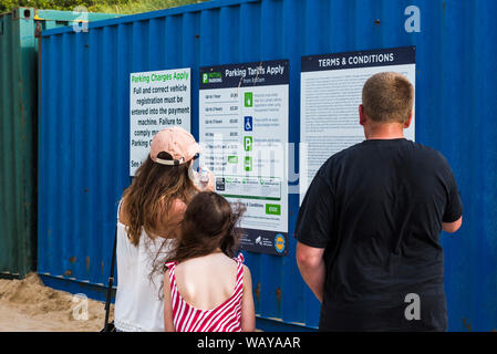 Eine Familie von Urlauber am Parkplatz Gebühren auf den Fistral Parkplatz in Newquay in Cornwall. Stockfoto