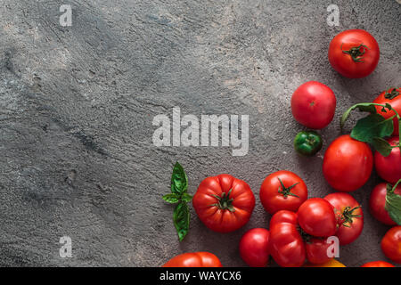 Frische Tomaten auf einen konkreten Hintergrund. Ansicht von oben mit der Kopie Raum Stockfoto