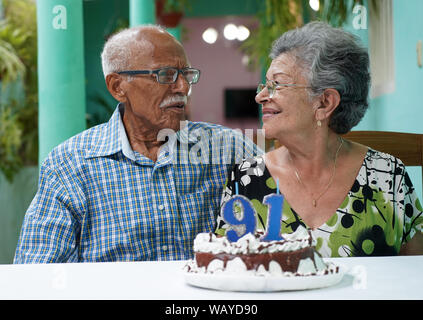 Ältere Paare mit einem Kuchen auf dem Tisch und die Nummer 91 auf dem Kuchen Stockfoto