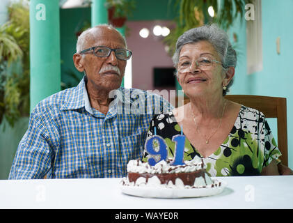 Ältere Paare mit einem Kuchen auf dem Tisch und die Nummer 91 auf dem Kuchen Stockfoto