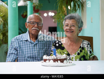 Ältere Paare mit einem Kuchen auf dem Tisch und die Nummer 1 auf dem Kuchen Stockfoto