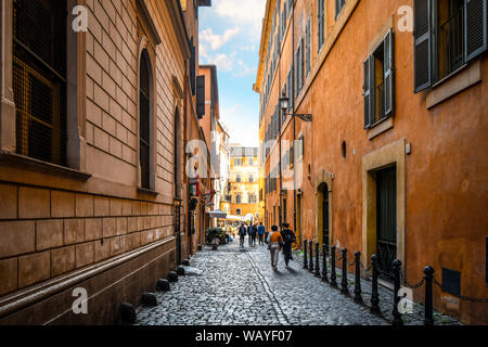 Italienische Geschäftsleute, Einheimische und Touristen zu Fuß einer schmalen, dunklen Gasse in Richtung Piazza in Rom, Italien Stockfoto