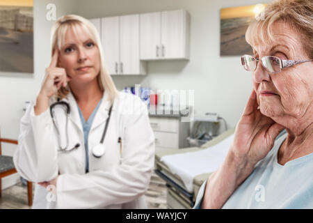 Einfühlsame Arzt Hinter Gestörte ältere Erwachsene Frau im Amt. Stockfoto