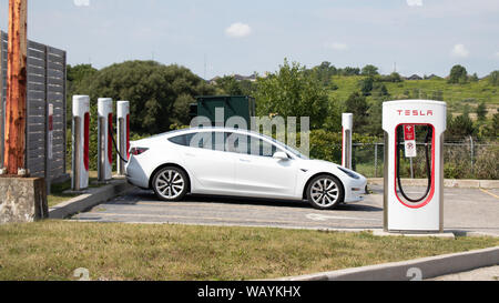 Tesla Modell 3 geparkt und der Ladevorgang bei Tesla Kompressor entfernt. Stockfoto