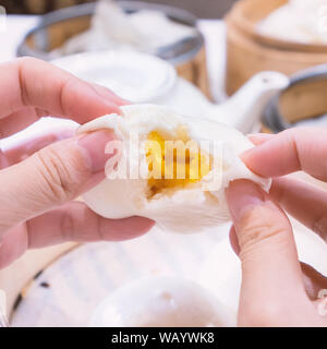 Köstliches Dim Sum, berühmten kantonesische Küche in Asien, frisch und heiß gesalzen cremige Vanillesauce Brötchen im Bambus Steamer in Hongkong yumcha Restaurant, in der Nähe Stockfoto