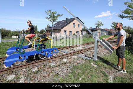 20. August 2019, Mecklenburg-Vorpommern, Waren (Müritz): Urlauber reisen mit dem Trolley zwischen den ehemaligen Güterbahnhof und die Mecklenburgische Schweiz Natur Park und eine Barriere muss vor dem Überqueren einer Straße geöffnet werden. Die Route der "raisine Mecklenburg" zwischen Waren (Müritz) und Schwinkendorf ist 13 Kilometer lang, kürzere Touren sind natürlich auch möglich. Wer will zu überholen die Katze mit seiner Front Mann austauschen müssen. Foto: Bernd Wüstneck/dpa-Zentralbild/ZB Stockfoto