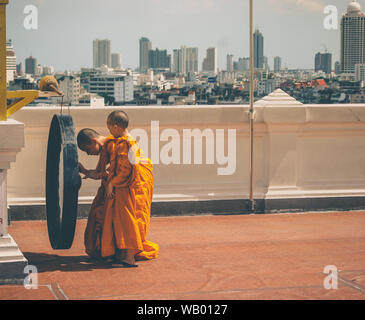 Buddhistische Mönche beten zu Buddha und der Stadt mit der Skyline im Hintergrund in Bangkok. Stockfoto