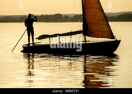 Lembruch, Deutschland. 22 Aug, 2019. Ein junger Mann drückt ein Segelboot mit einem Stick zurück in den Hafen auf dem Dümmer See im Landkreis Diepholz. Credit: Hauke-Christian Dittrich/dpa/Alamy leben Nachrichten Stockfoto